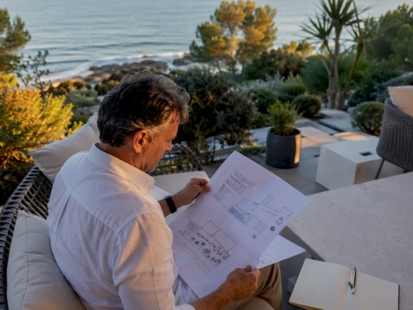 Un hombre analiza unos planos en una exclusiva villa frente al mar.