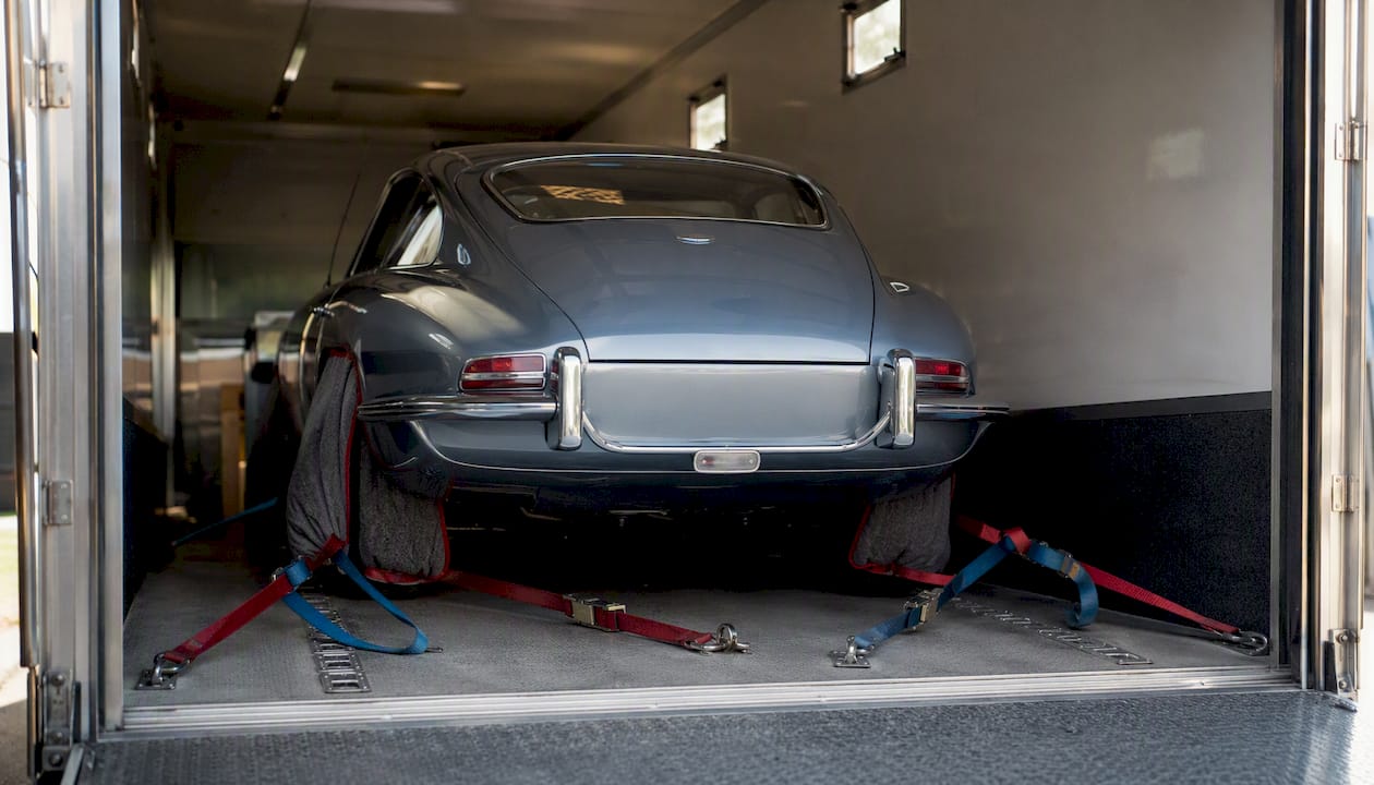Classic car secured with straps inside enclosed trailer