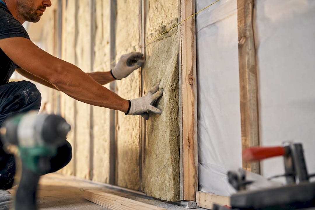 Hands installing insulation panels on home wall